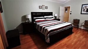Een slaapkamer met een bed, twee nachtkastjes, een stoel en een deur.