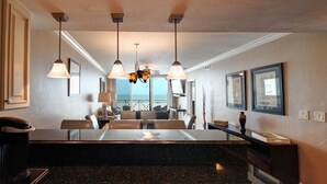Une cuisine moderne dotée d’un îlot central, de luminaires suspendus et offrant une vue sur l’extérieur.