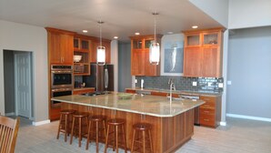 Una cocina moderna con armarios de madera, electrodomésticos de acero inoxidable y una isla central con taburetes de bar.