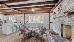 A spacious kitchen with a central island, wooden beams, and a brick fireplace. - Kennebunkport Summer Rental walk to Dock Square! PET Friendly! (Kennebunkport)