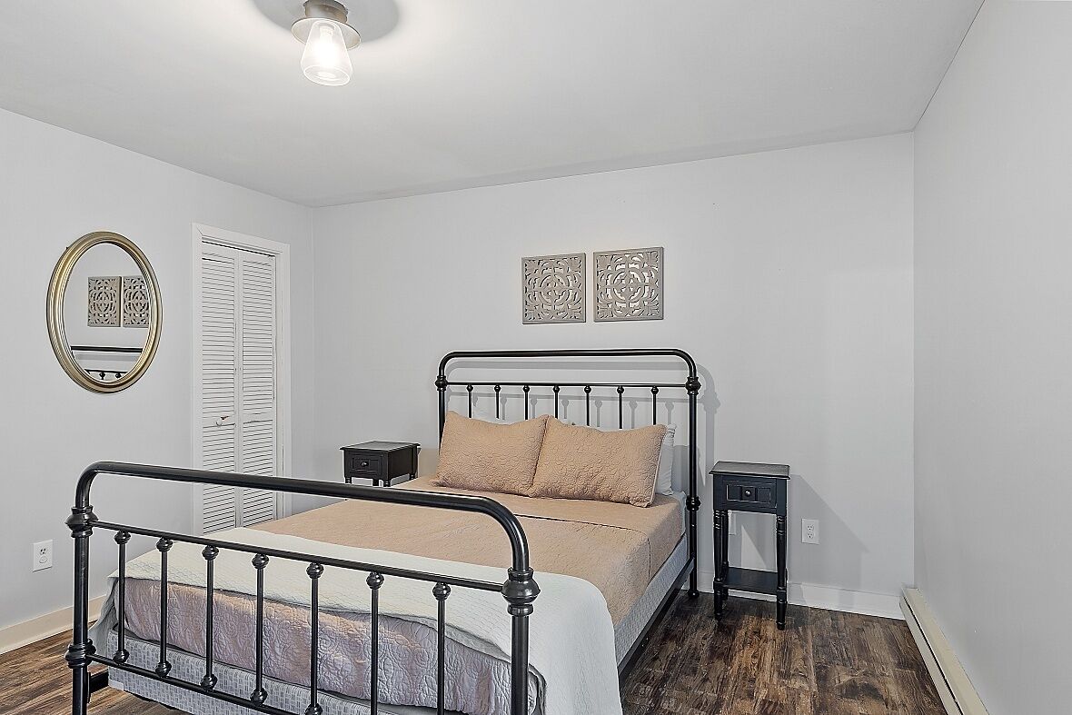 Une chambre à coucher avec un cadre de lit en métal, une table de chevet, une commode, un miroir et deux éléments décoratifs fixés au mur.