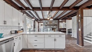 A spacious kitchen with white cabinetry, a central island, and exposed wooden beams. - Kennebunkport Summer Rental walk to Dock Square! PET Friendly! (Kennebunkport)