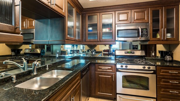 A modern kitchen with stainless steel appliances, wooden cabinets, and a granite countertop. - Condo within walking distance of the strip (Las Vegas)