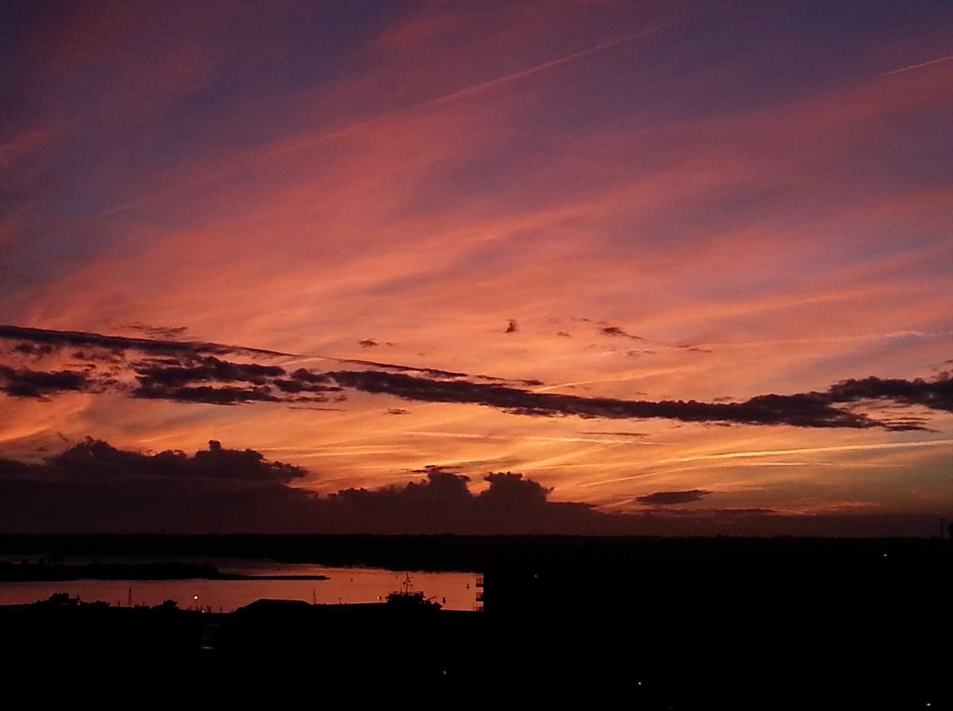 A sunset over a body of water with a silhouette of a city skyline in the foreground.