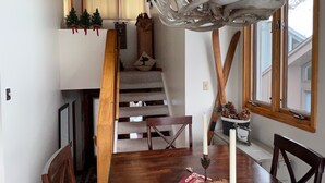 A dining area with a wooden table, chairs, a chandelier, and a staircase leading to an upper level.