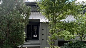 A modern building with a metal roof, a covered entrance, and a gravel pathway leading to the door.