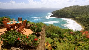 A table set outdoors with a view of the ocean and a hillside. - Elegant Villa in Private Hope Bay. Infinity Pool with Sea View. (Bequia)