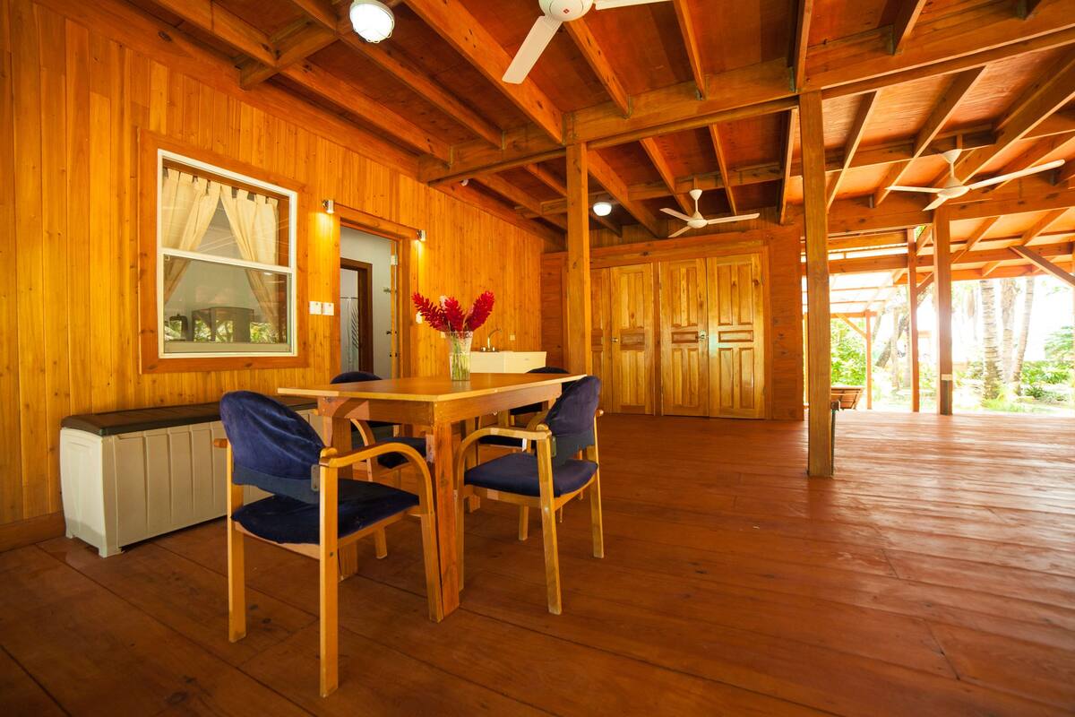 Un interior de madera con una mesa de comedor y sillas, un radiador y una ventana con cortinas.