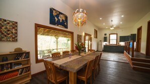 Un comedor con una mesa y sillas de madera, una lámpara de araña con forma de globo y una estantería llena de libros.