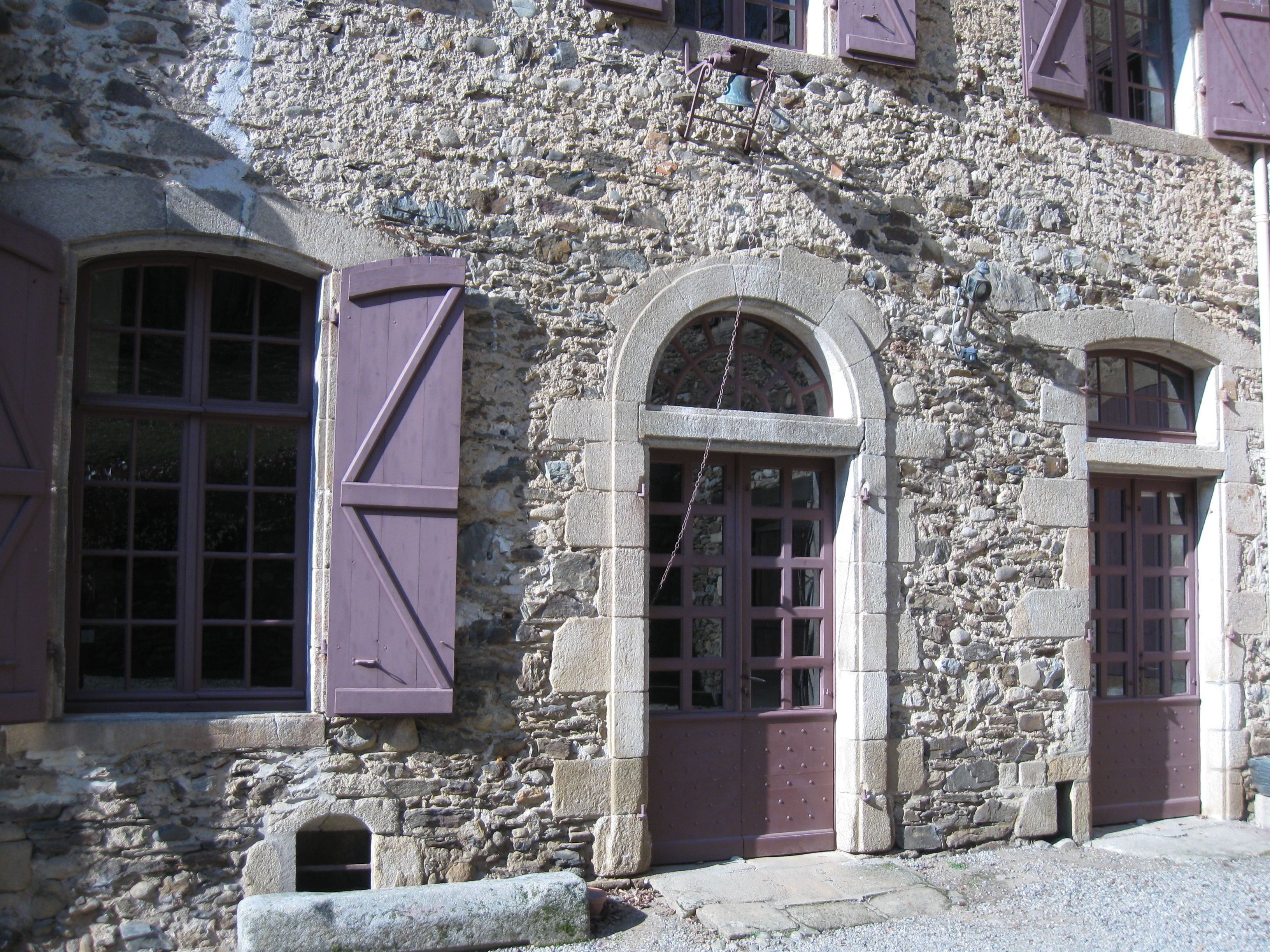 Un edificio de piedra con ventanas arqueadas y contraventanas.