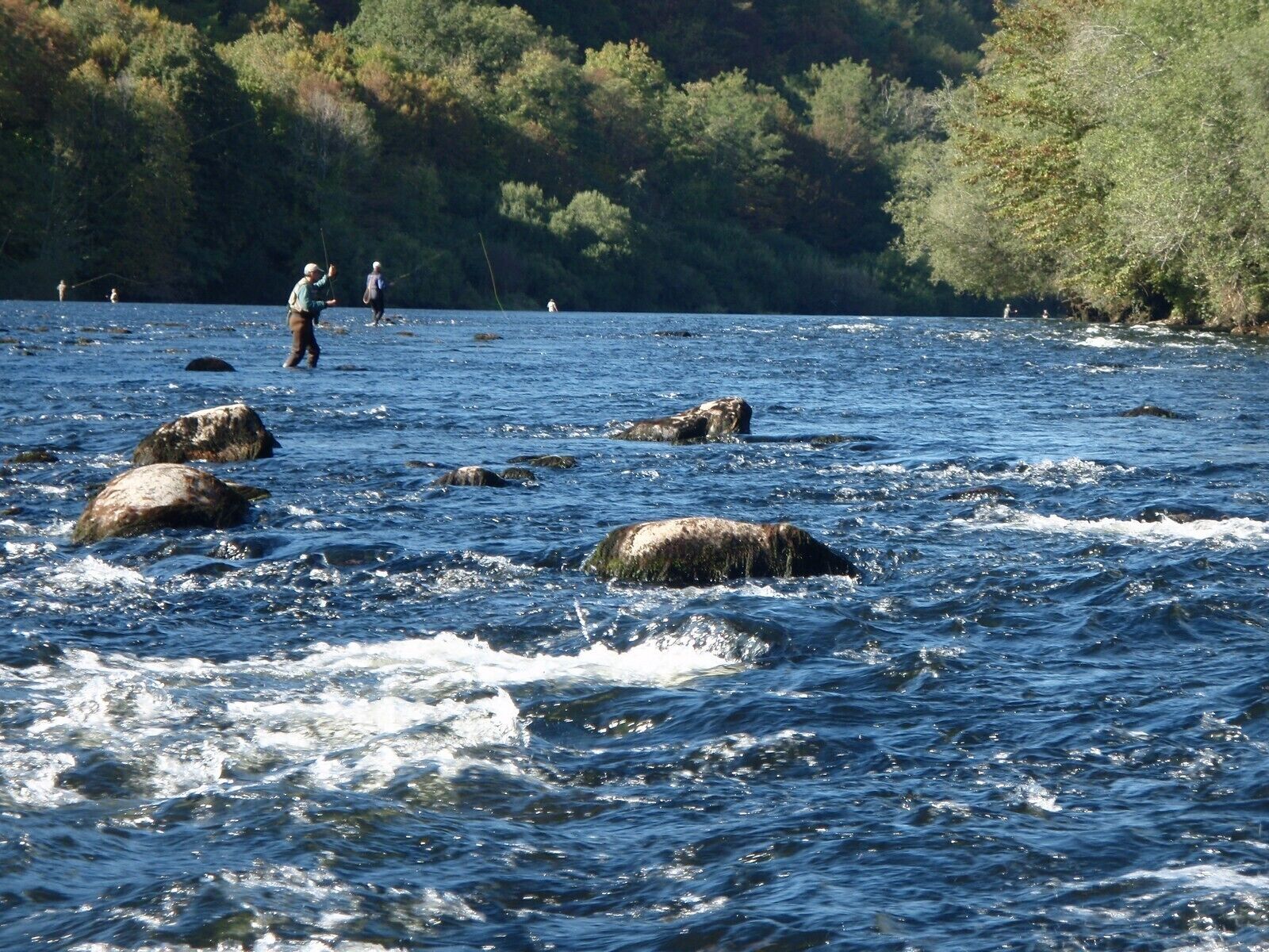 A river with rocks and people fishing.