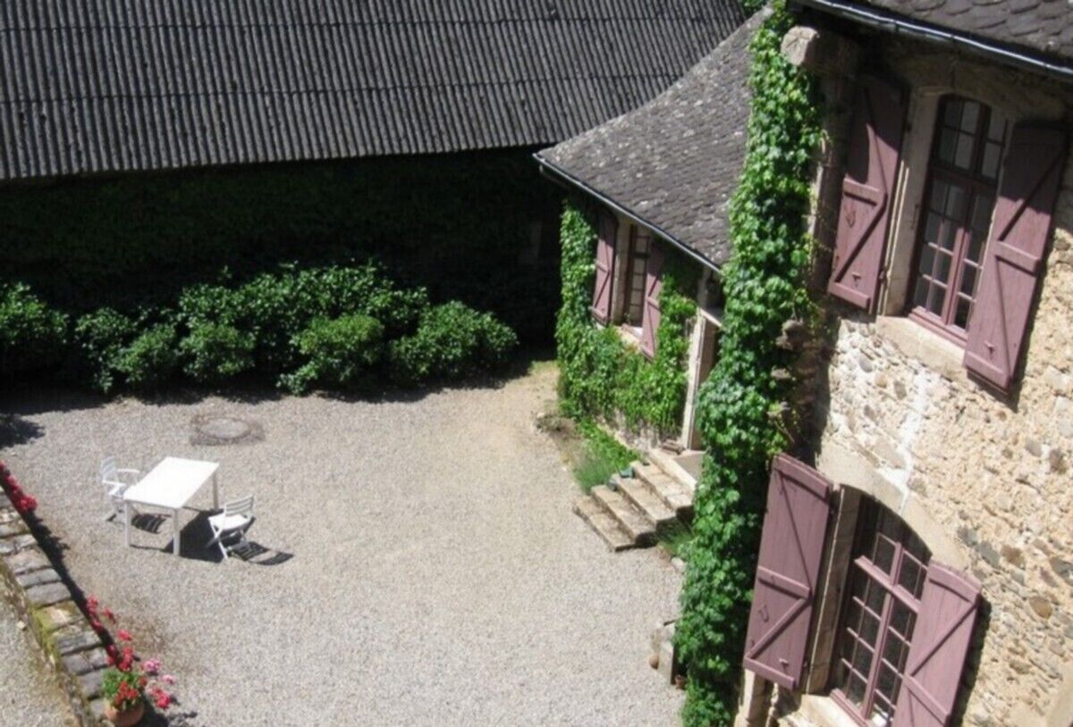 A stone building with a gravel courtyard, a table and chairs, and a small garden area.