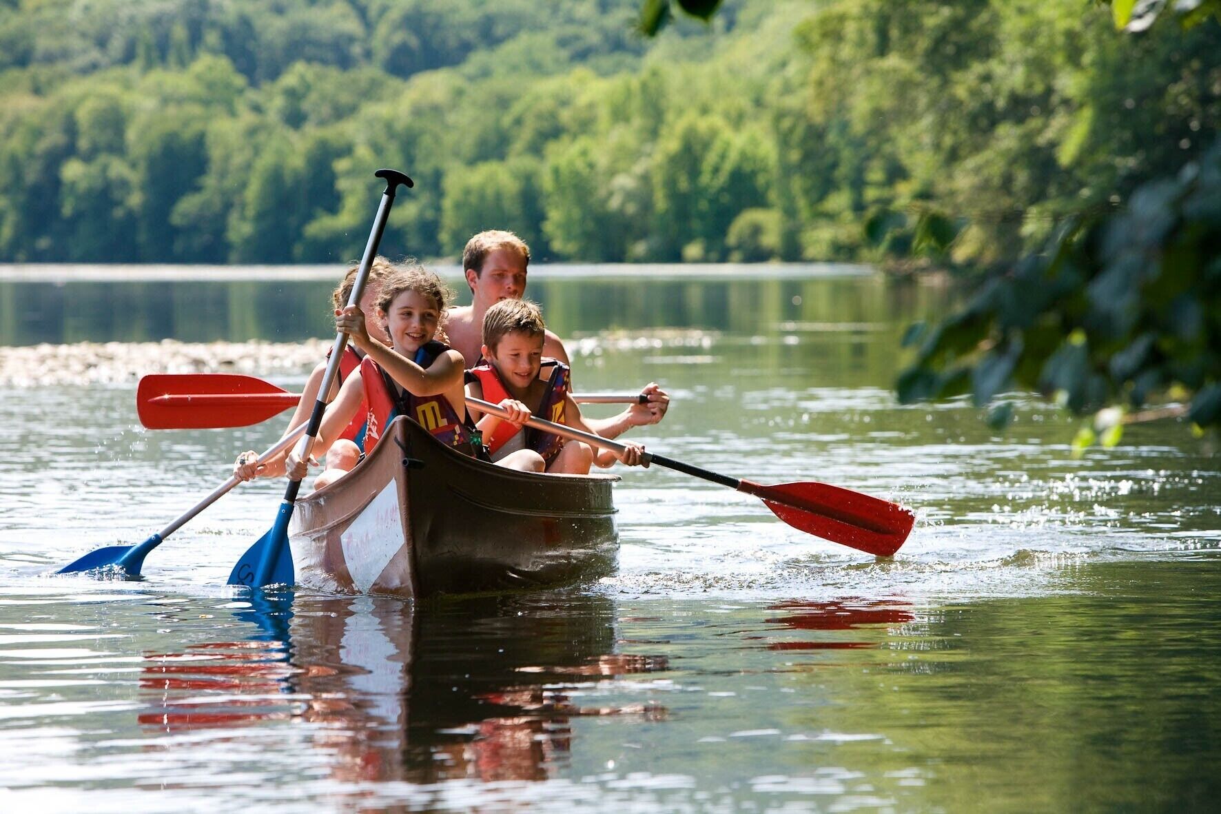 Un grup de persones en una canoa a un riu tranquil envoltat de vegetació.