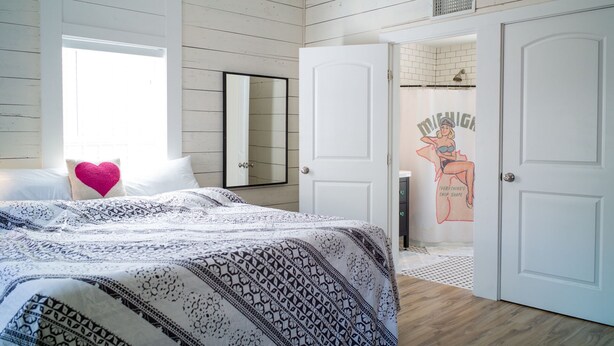 Una camera da letto con un letto, uno specchio e una porta che dà su un bagno.
