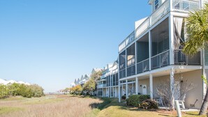 A coastal hotel with multiple balconies, a covered outdoor area, and a view of the beach. - Water's Edge 83 - Comfy Cool - Pool - River Views - Close to Everything - Beautifully Updated (Folly Beach)