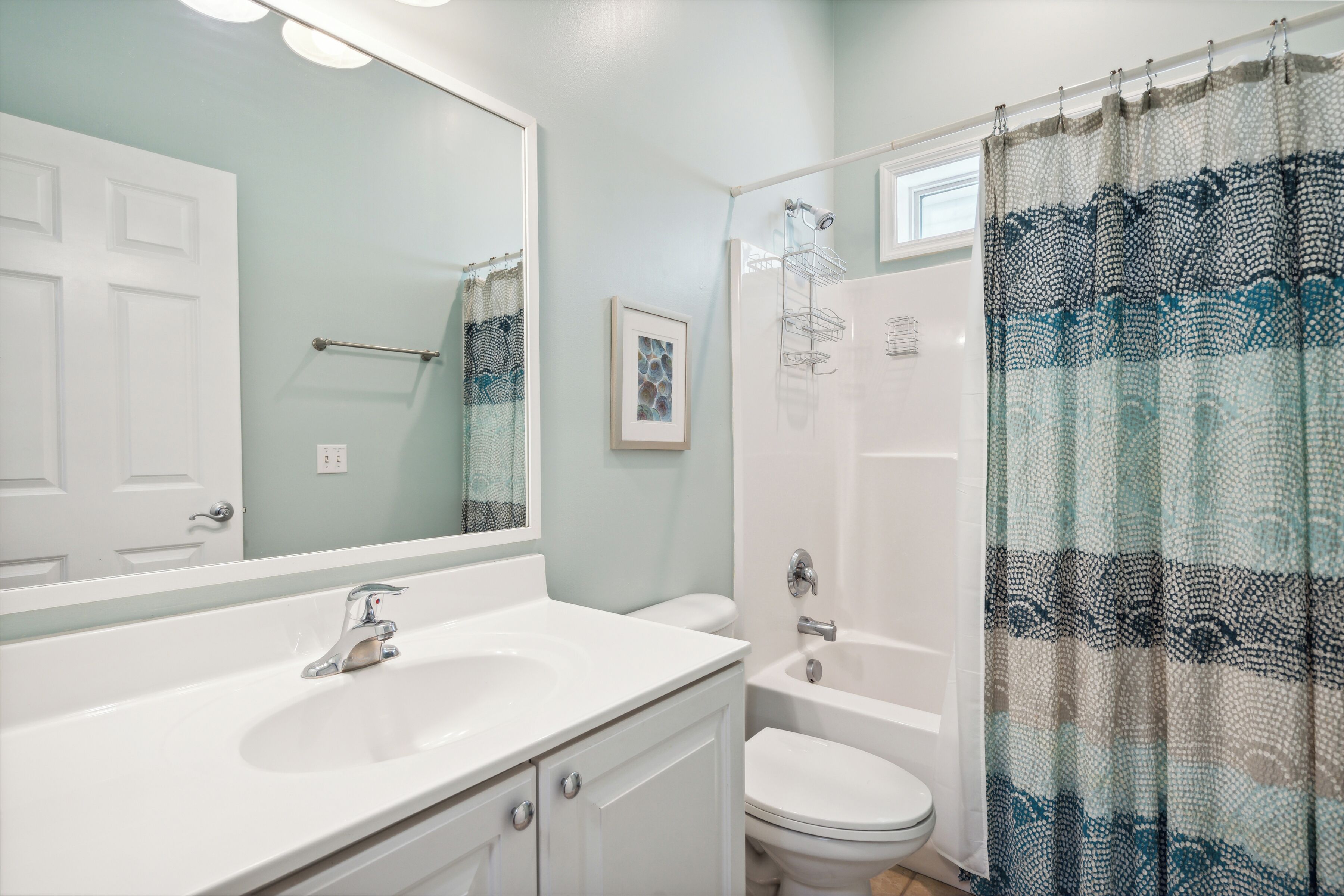 A bathroom with a white sink, a toilet, a bathtub, and a shower curtain.