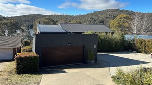 A modern building with a garage, surrounded by a well-maintained lawn and a view of a hilly landscape.