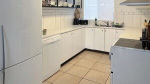 A compact kitchen with white cabinets, a built-in dishwasher, and a window above the sink.