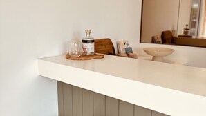 A bathroom with a white countertop, a wooden stool, a bottle of Native Spirits, and a mirror. - Devonlea Olive Grove
4br Home with pool on 8acres- next door to The Cups Estate (Fingal)