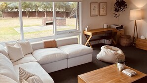 A modern living room with a sectional sofa, a wooden coffee table, and a desk with a chair. - Devonlea Olive Grove
4br Home with pool on 8acres- next door to The Cups Estate (Fingal)