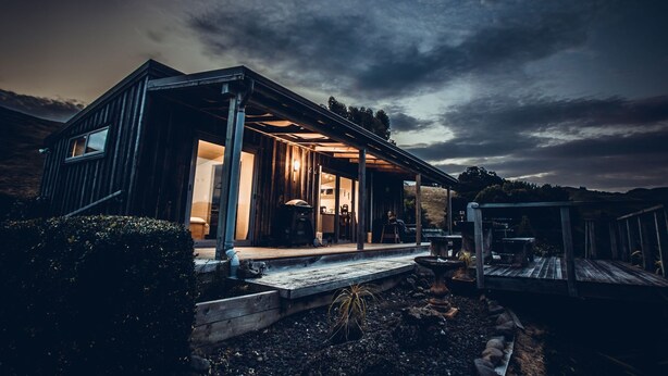 Uma casa moderna com varanda coberta, cozinha aparente e uma grande janela.