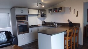 Uma cozinha moderna com armários brancos, uma ilha central, fogão a gás e uma pia.