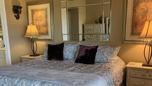 Ein Schlafzimmer mit einem großen Bett, zwei Nachttischen, einem Schminktisch, einem Spiegel und einer Kommode.