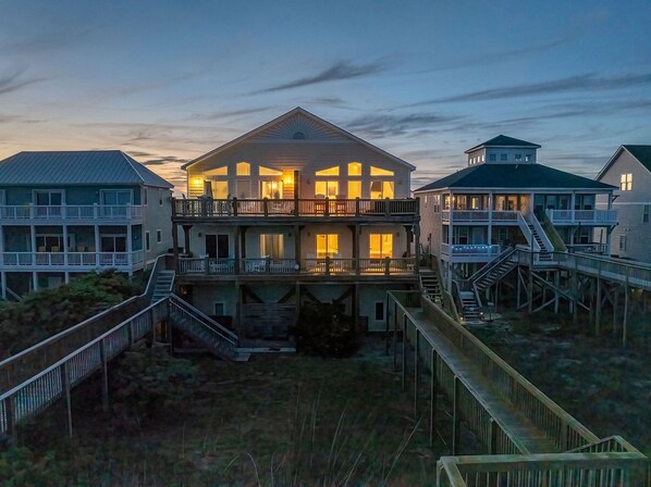 A multi-story beachfront property with a prominent central building featuring balconies and a covered outdoor area.
