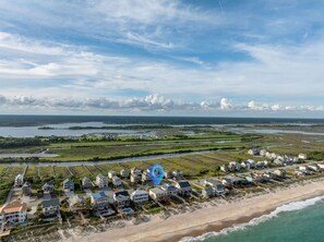 Une zone résidentielle côtière, avec des maisons le long de la plage et une vaste étendue d’eau en arrière-plan.