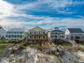 A beachfront property with multiple buildings, wooden walkways, and a sandy beach. - Toes in the Water - Luxury Oceanfront 5 BR 5.5 Bath; Hot Tub; Elevator (North Topsail Beach)