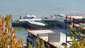A waterfront building with a glass facade, a covered pedestrian bridge, and a dock with boats.