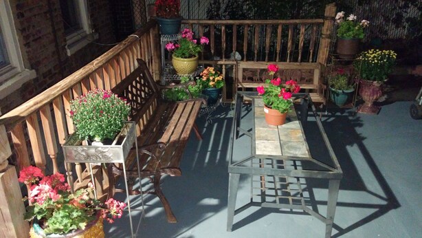 A wooden bench and table with potted plants in a courtyard.