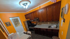A compact kitchen with wooden cabinets, a stainless steel refrigerator, a microwave, and a granite countertop.