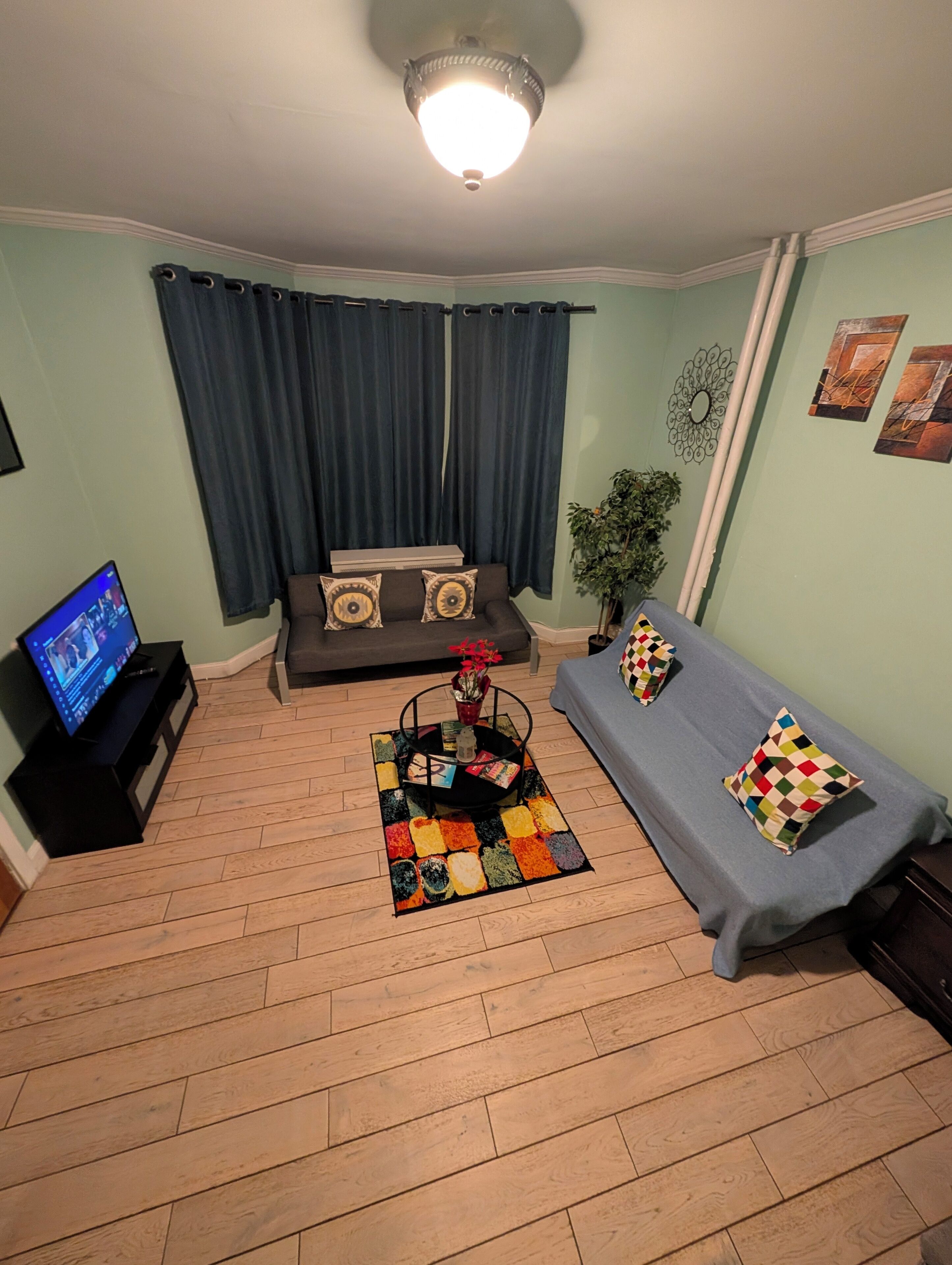 Een woonkamer met een bank, een salontafel, een televisie en een tapijt met dessin.