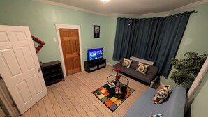 A living room with a sofa, a television, a coffee table, and a door.