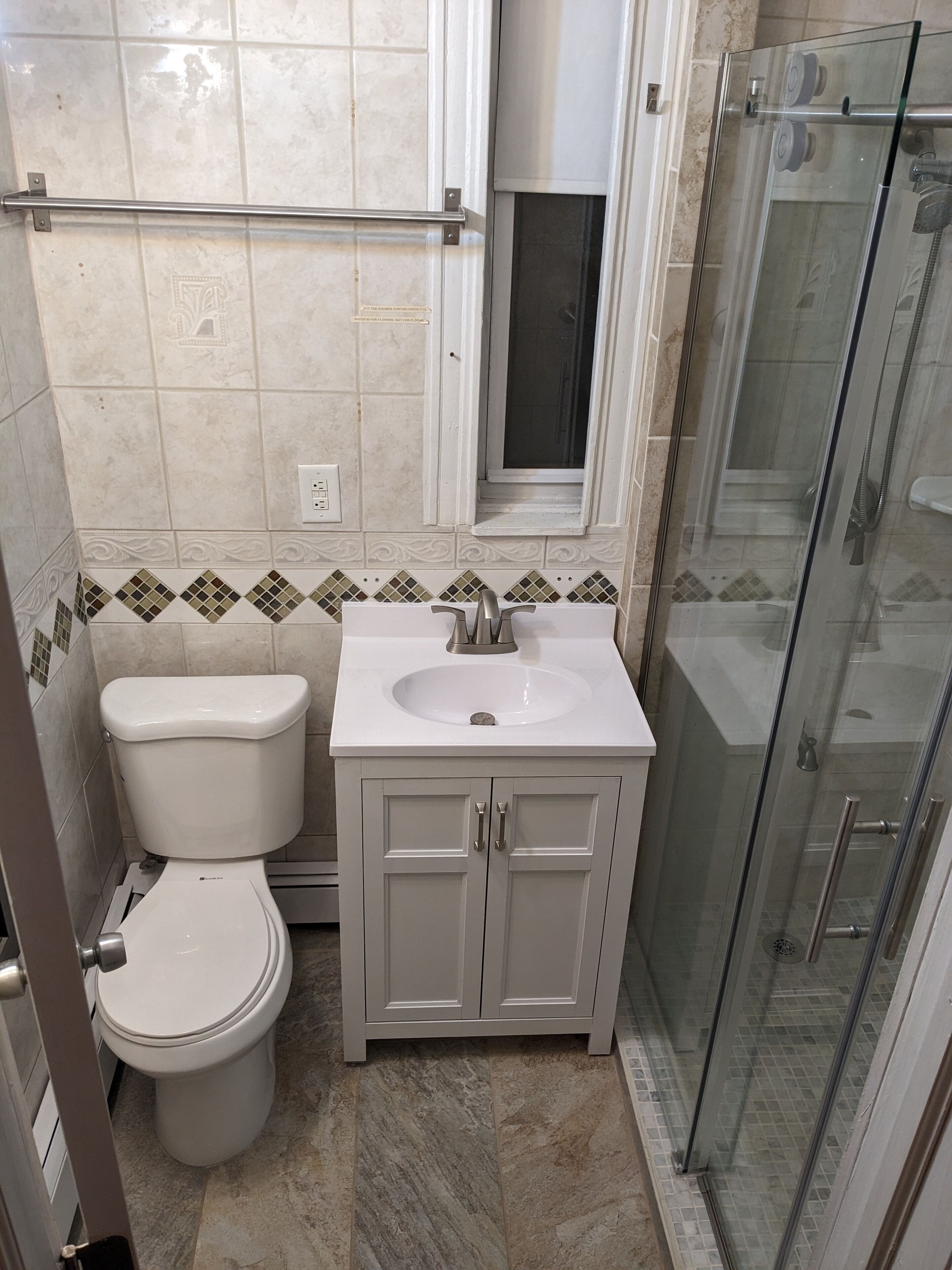 Une salle de bain équipée de toilettes, d’un lavabo et d’une douche à parois en verre.