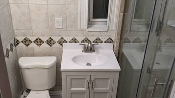 Une salle de bain équipée de toilettes, d’un lavabo et d’une douche à parois en verre.