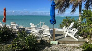 A beach view with white lounge chairs and umbrellas, a wooden deck, and a sign reading "Beach View". - Beachfront large 2/2 on Spanish Wells' northside beach. Sun deck by the water. (Spanish Wells)