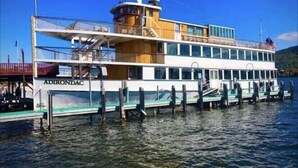 Un grand bateau à vapeur à plusieurs ponts, portant le nom « Adirondac » sur sa coque, était amarré à un quai.