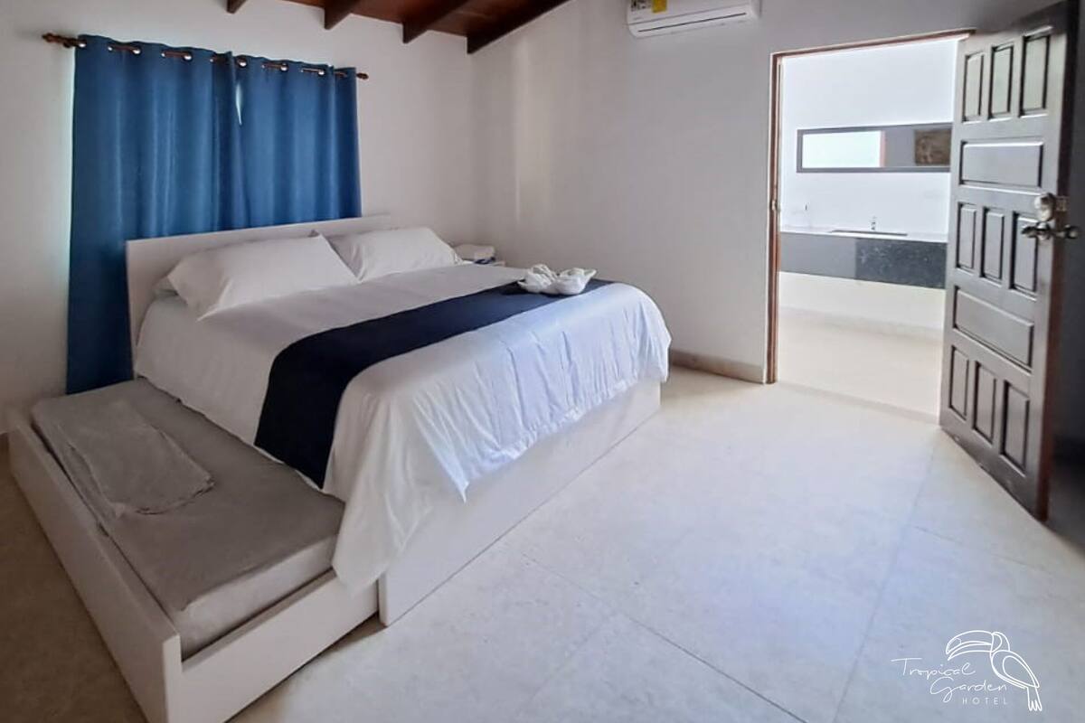 A bedroom with a bed, a bedside table, a ceiling fan, and an air conditioning unit.