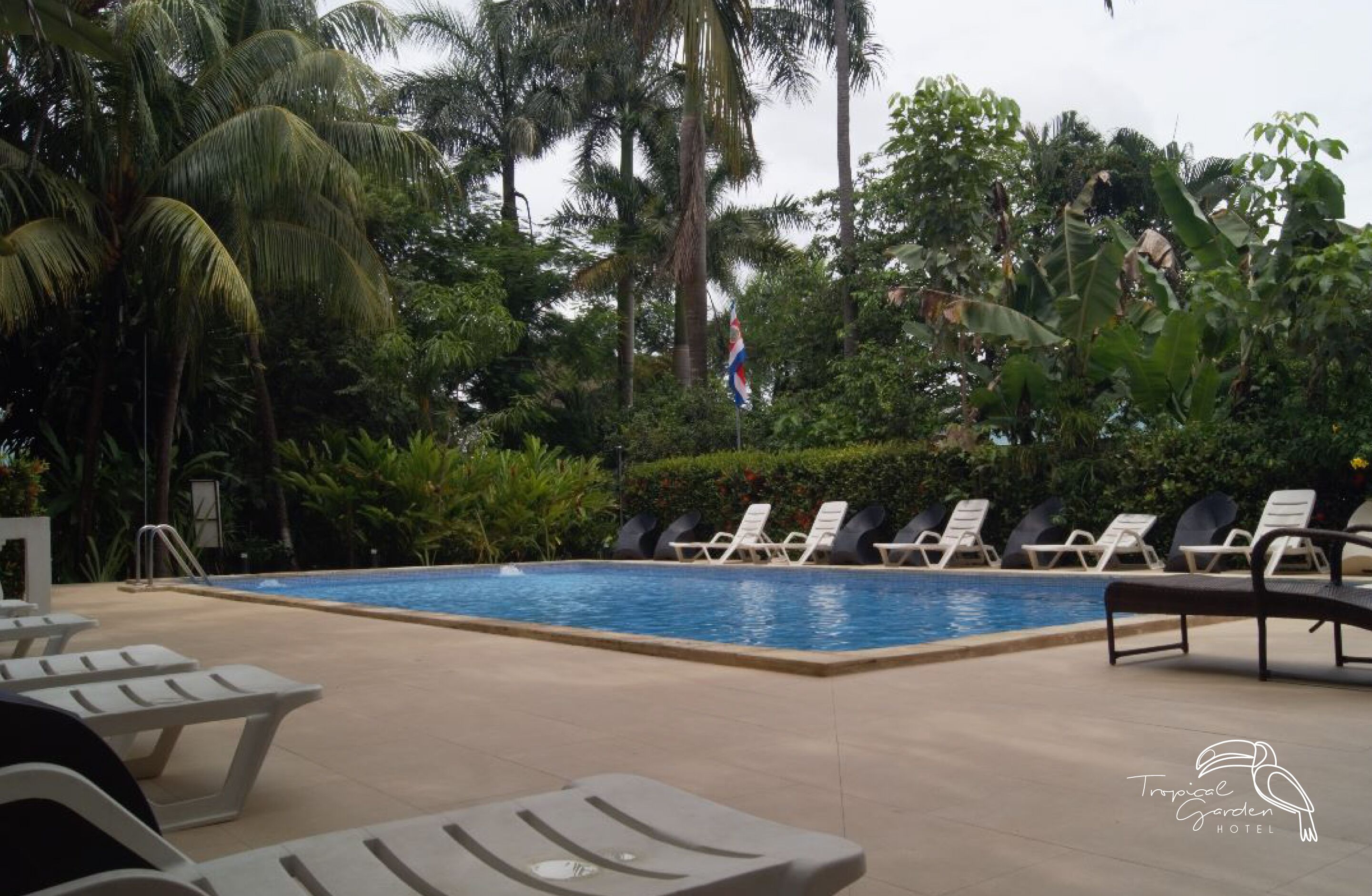 A pool area with lounge chairs and a flag.