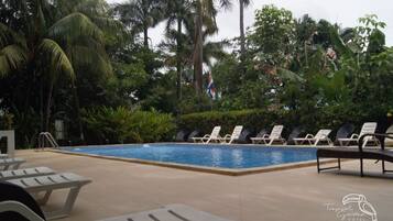 A pool area with lounge chairs and a flag.
