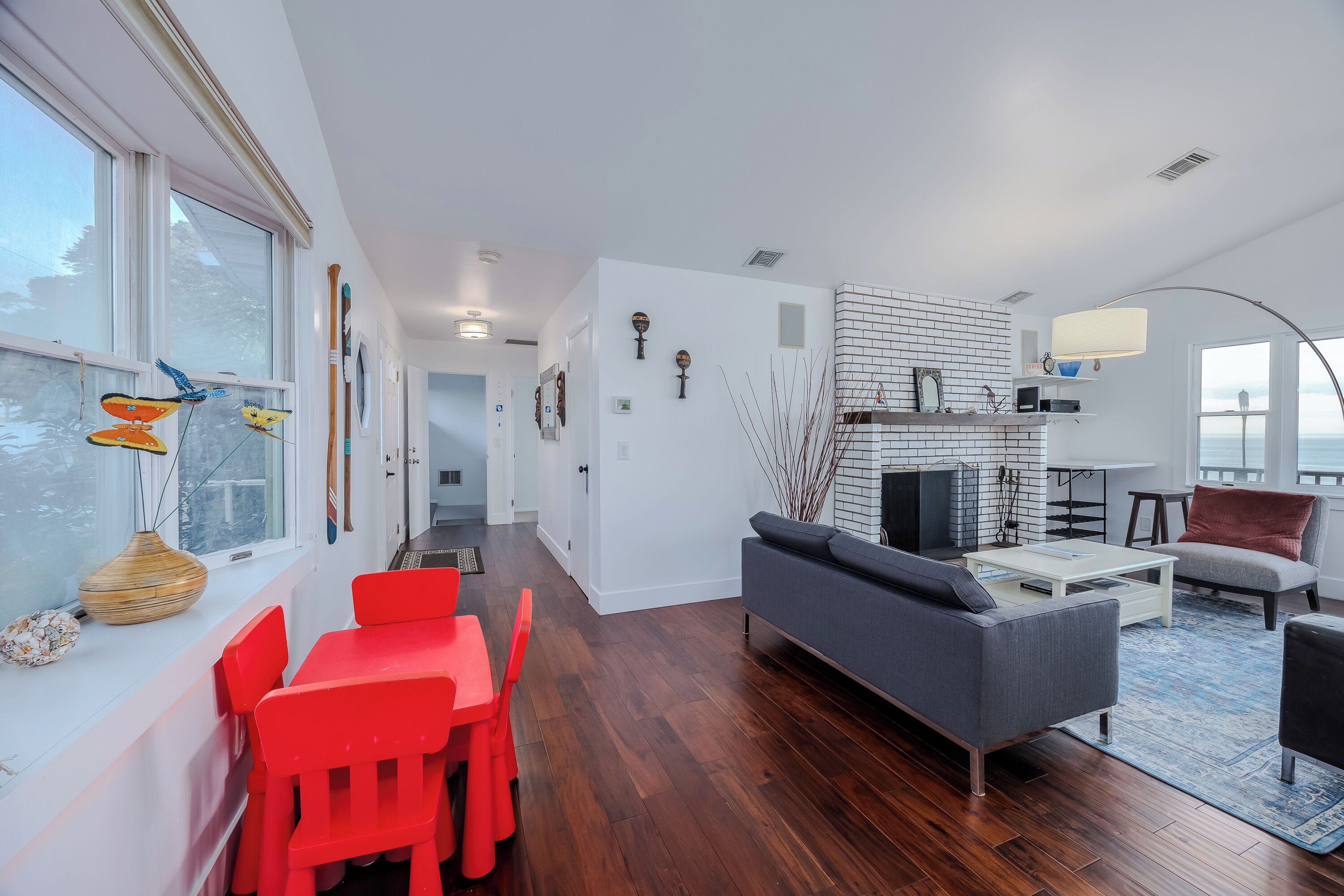 Una sala de estar moderna con chimenea, un comedor con sillas rojas y un sofá.