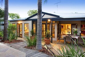 Een modern huis met een terras, grote ramen en een eethoek.