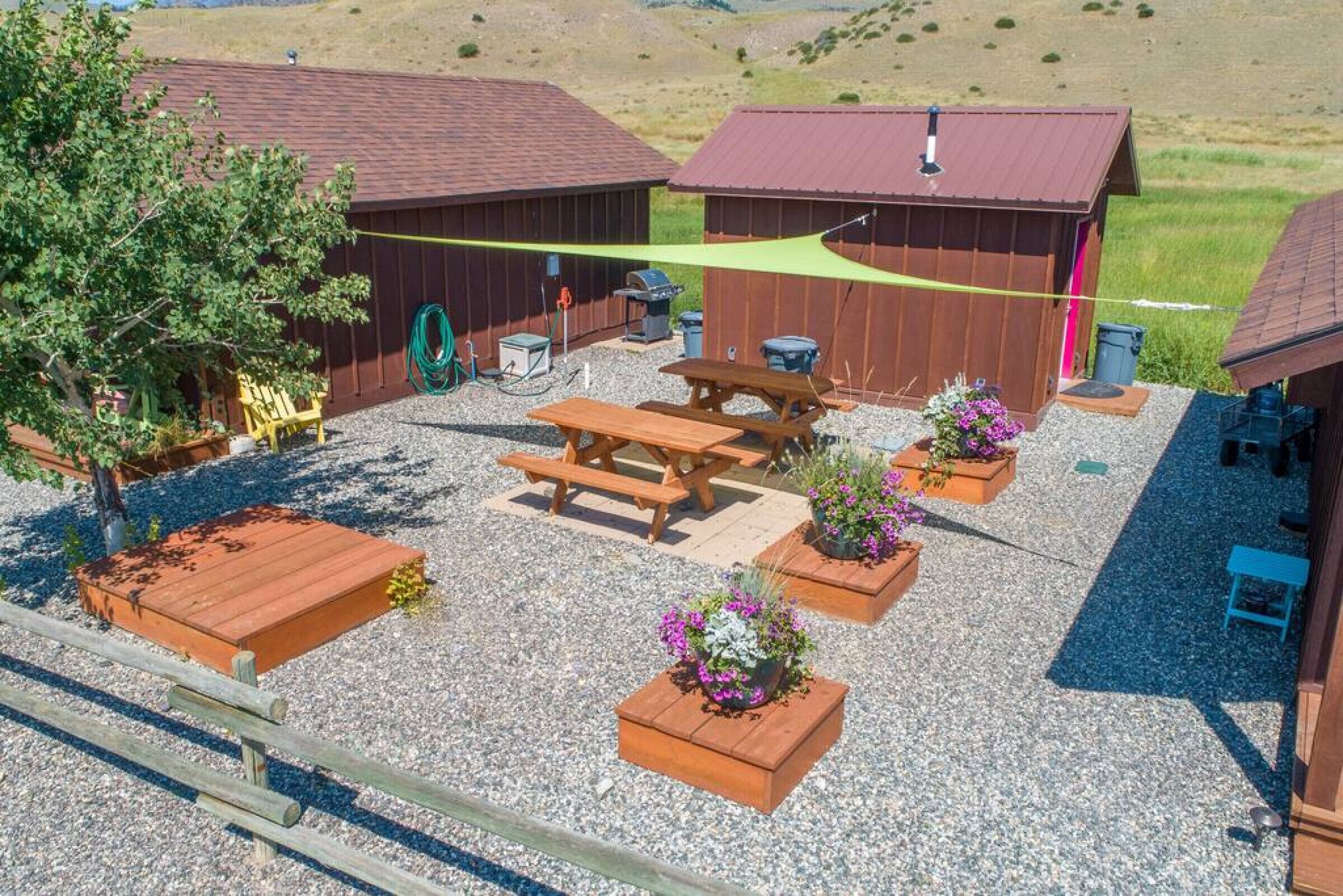 Un espace extérieur aménagé avec des bancs en bois, des tables de pique-nique et des jardinières fleuries.