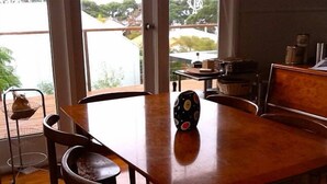 A dining area with a wooden table and chairs, a decorative vase, and a view of the outside through large windows.