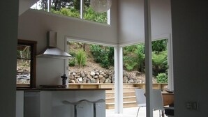 Een moderne keuken met een centraal eiland, barkrukken en uitzicht op een aangelegde tuin.