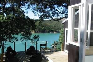 A wooden deck with outdoor seating, overlooking a calm lake and forested hills.