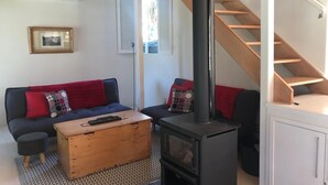 Een woonkamer met een bank, een houten salontafel, een open haard en een trap.