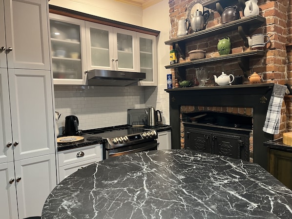 A kitchen with white cabinets, a black marble countertop, a brick wall, and a black oven.